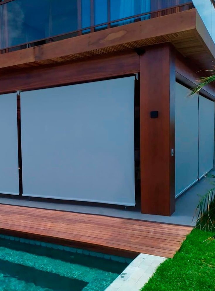 Toldo cortina blecaute protegendo varanda com deck e piscina
