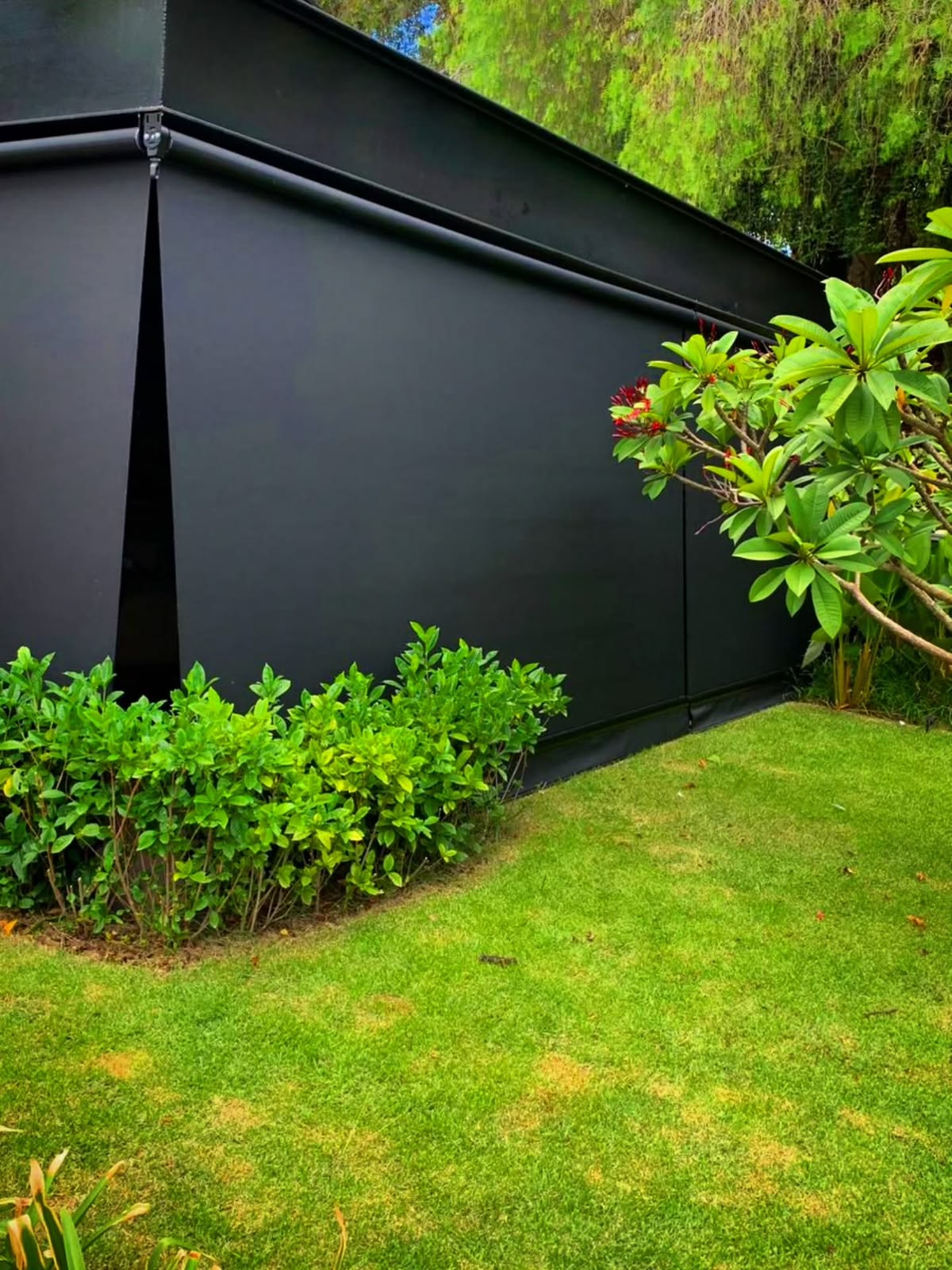 Toldo cortina blecaute preto instalado em área de jardim