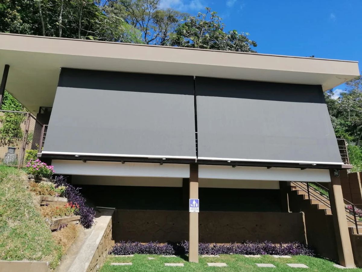 Toldo cortina blecaute instalado em varanda com vista para o jardim