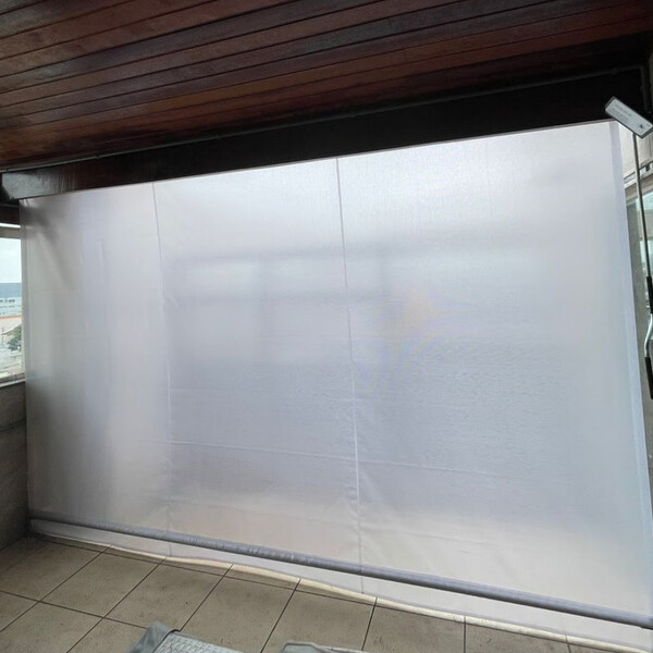Toldo cortina translúcido fechado em varanda, difundindo a luz do sol