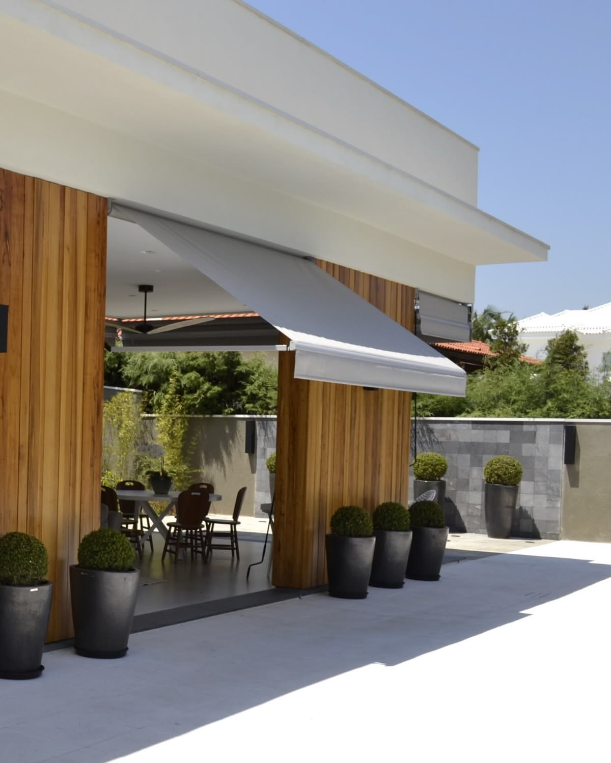 Área gourmet coberta por toldo retrátil de braço reto com lona clara