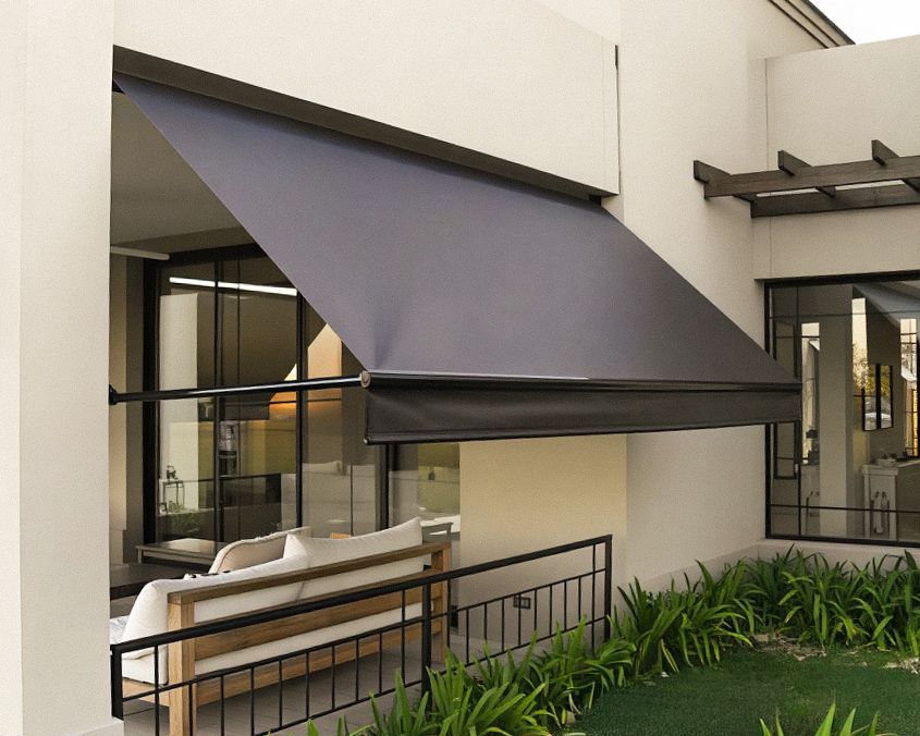 Toldo retrátil de braço reto com lona escura sobre área de estar externa
