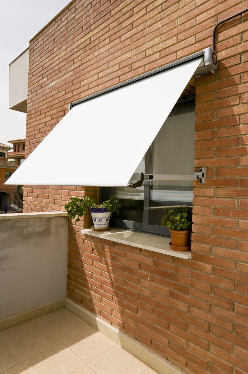 Toldo de braço reto instalado sobre janela de fachada
